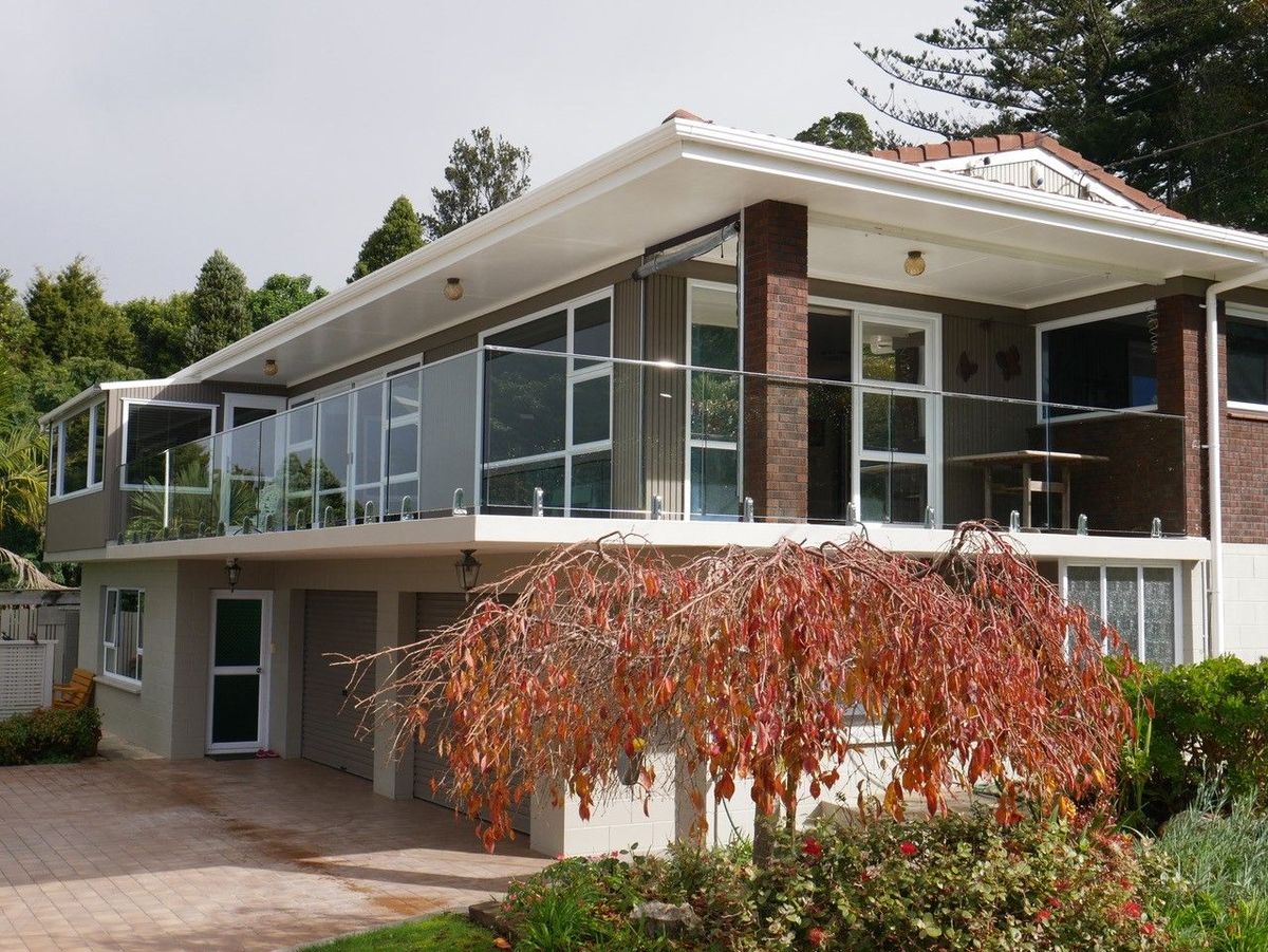 A balcony on a brick home with a frameless glass railing